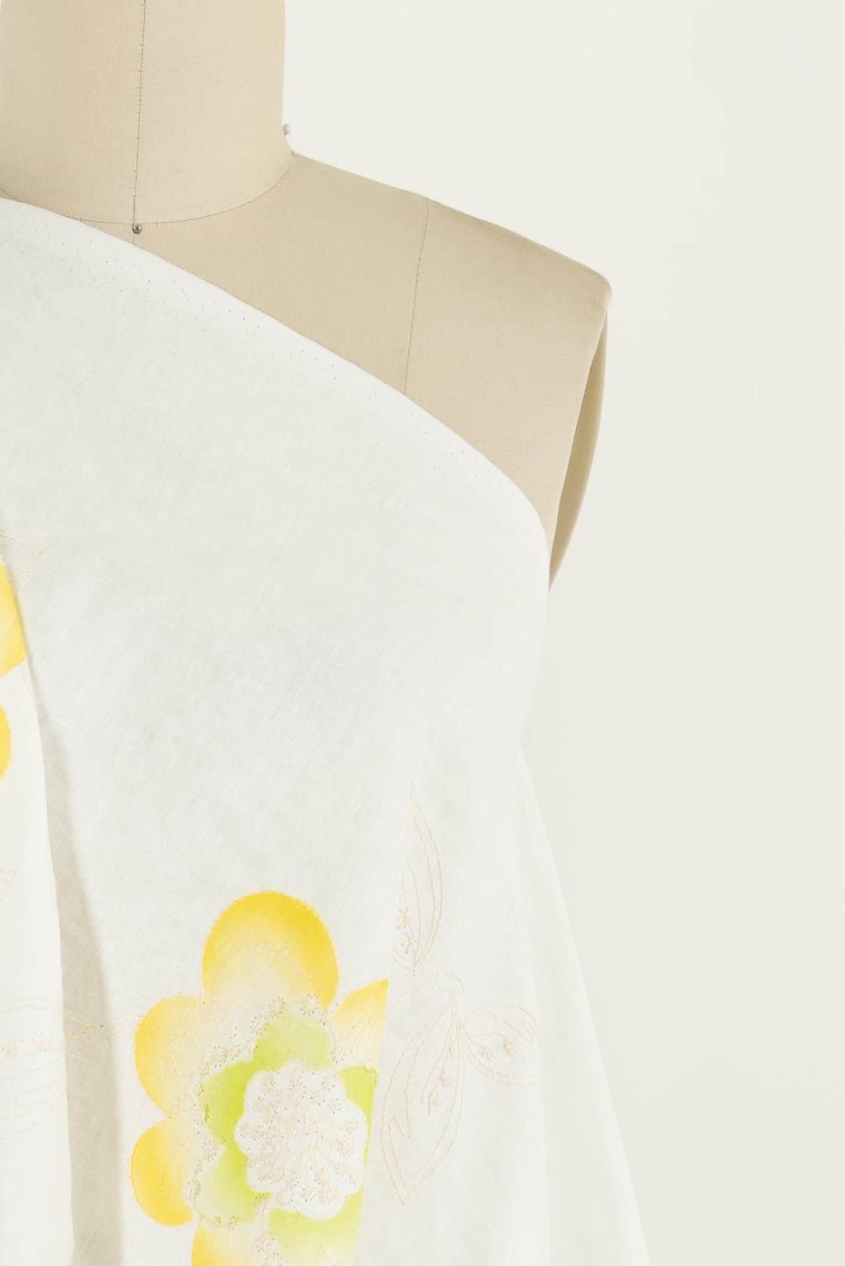 White fabric with yellow floral print draped on mannequin, ideal for apparel sewing projects