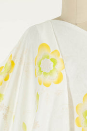 White fabric with yellow and green floral print, ideal for apparel sewing and quilting projects