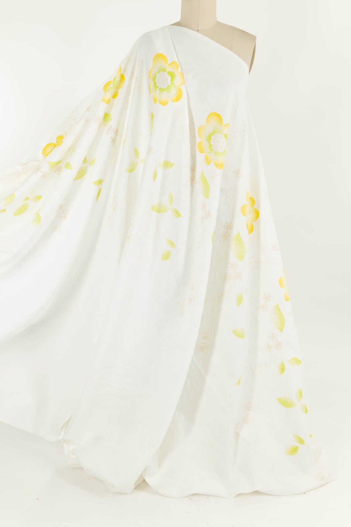 White fabric with yellow and green floral print, ideal for apparel sewing projects
