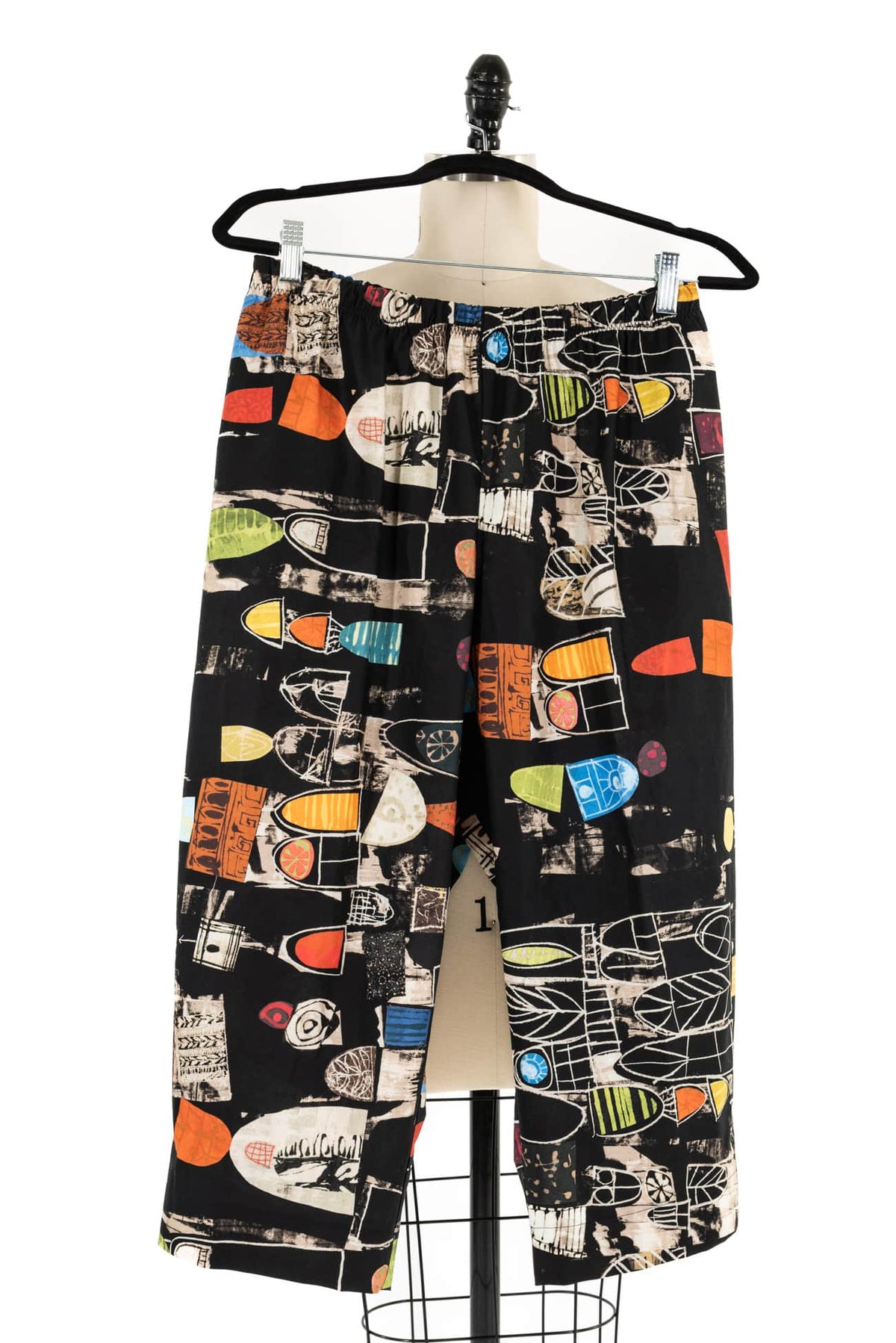 Black abstract print pants with colorful geometric shapes, displayed on mannequin for sewing projects