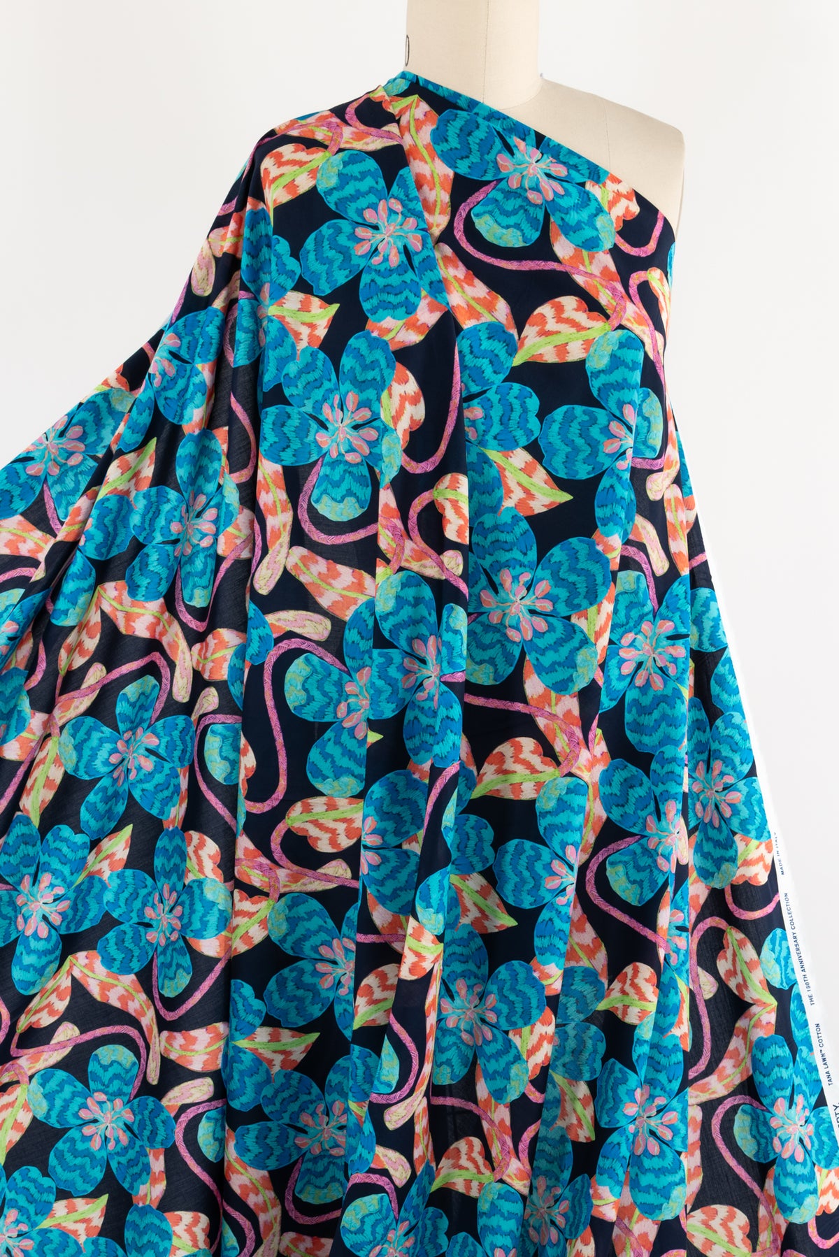 Vibrant floral print fabric with blue, pink, and orange blooms on dark background, ideal for apparel sewing