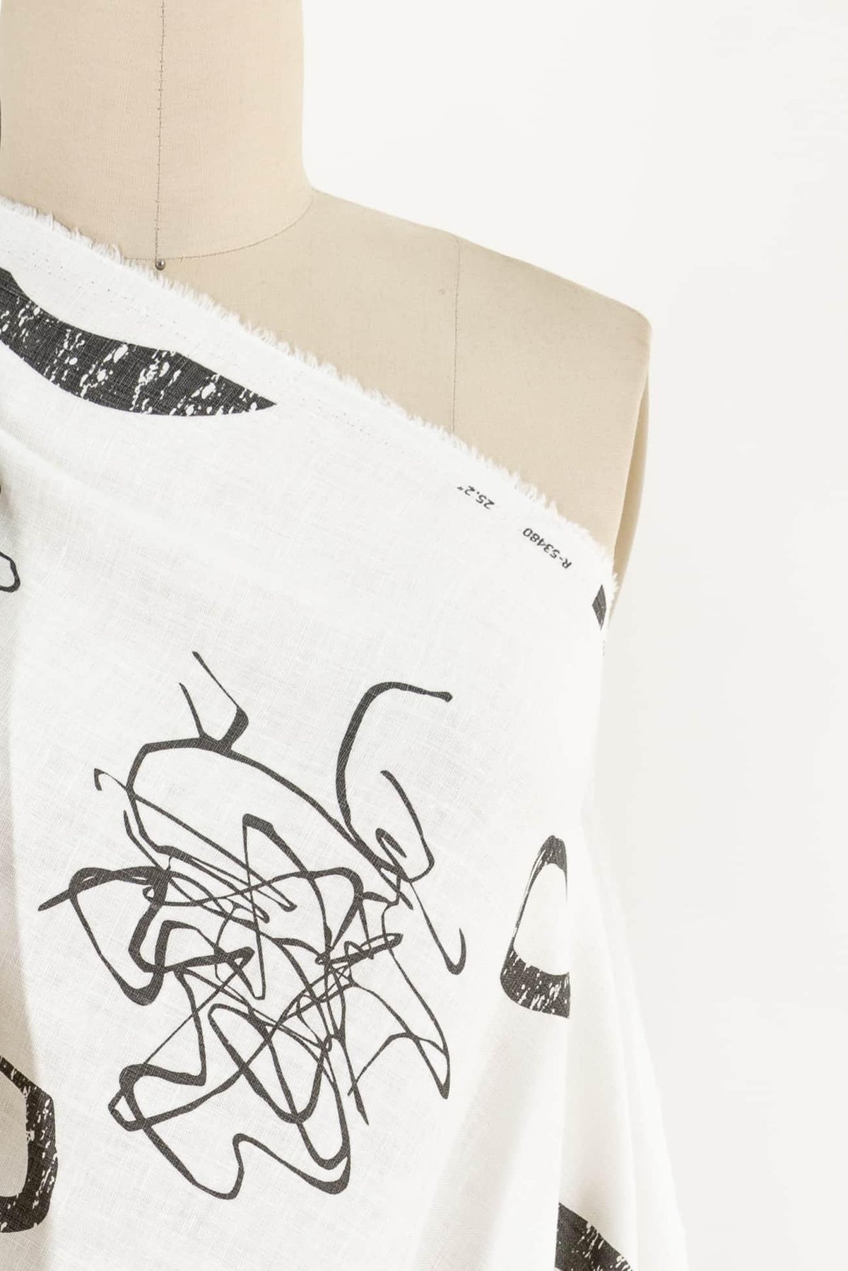 White fabric with black abstract line print, displayed on mannequin for apparel sewing