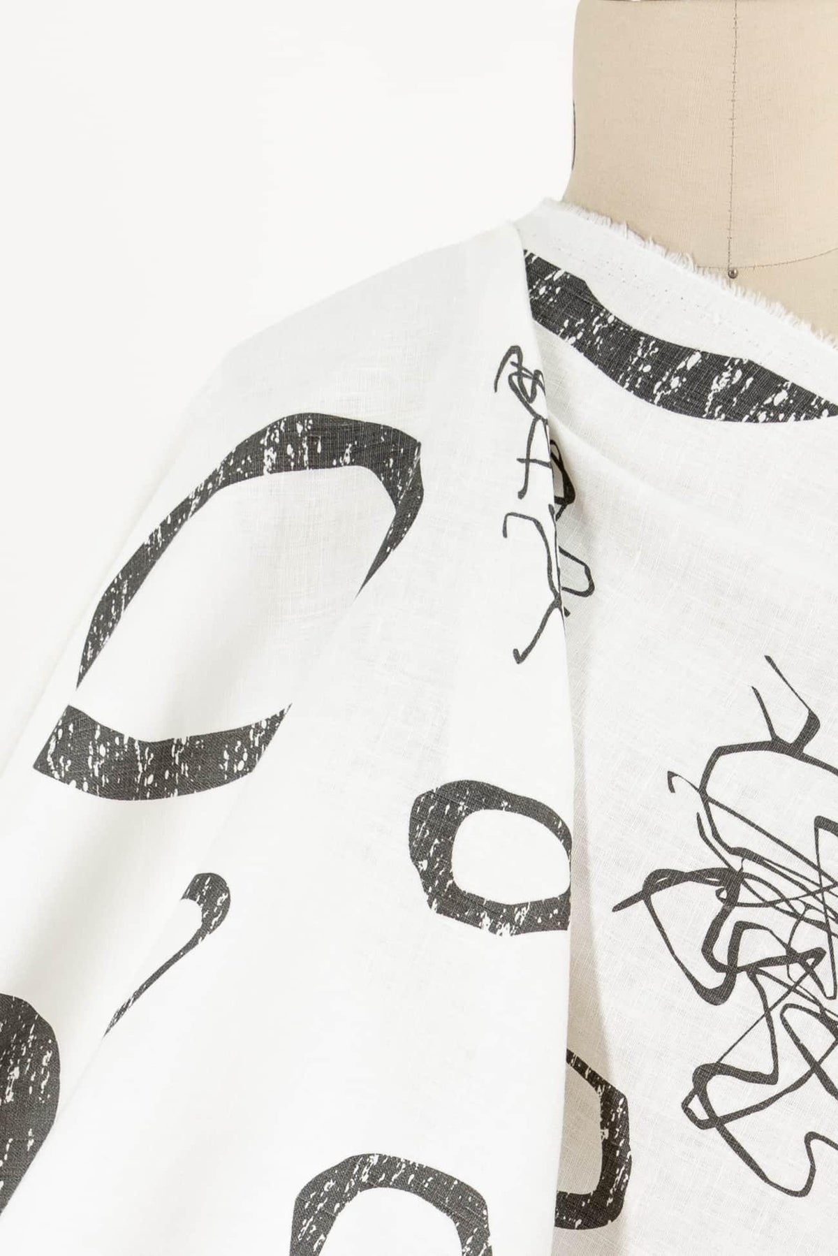 White fabric with bold black abstract print, ideal for fashion sewing and apparel projects