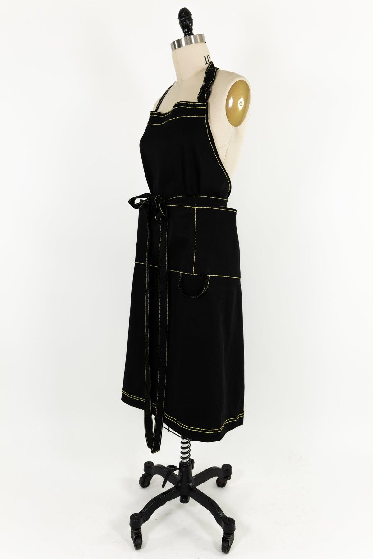 Black apron with yellow stitching on mannequin, ideal for sewing and crafting projects
