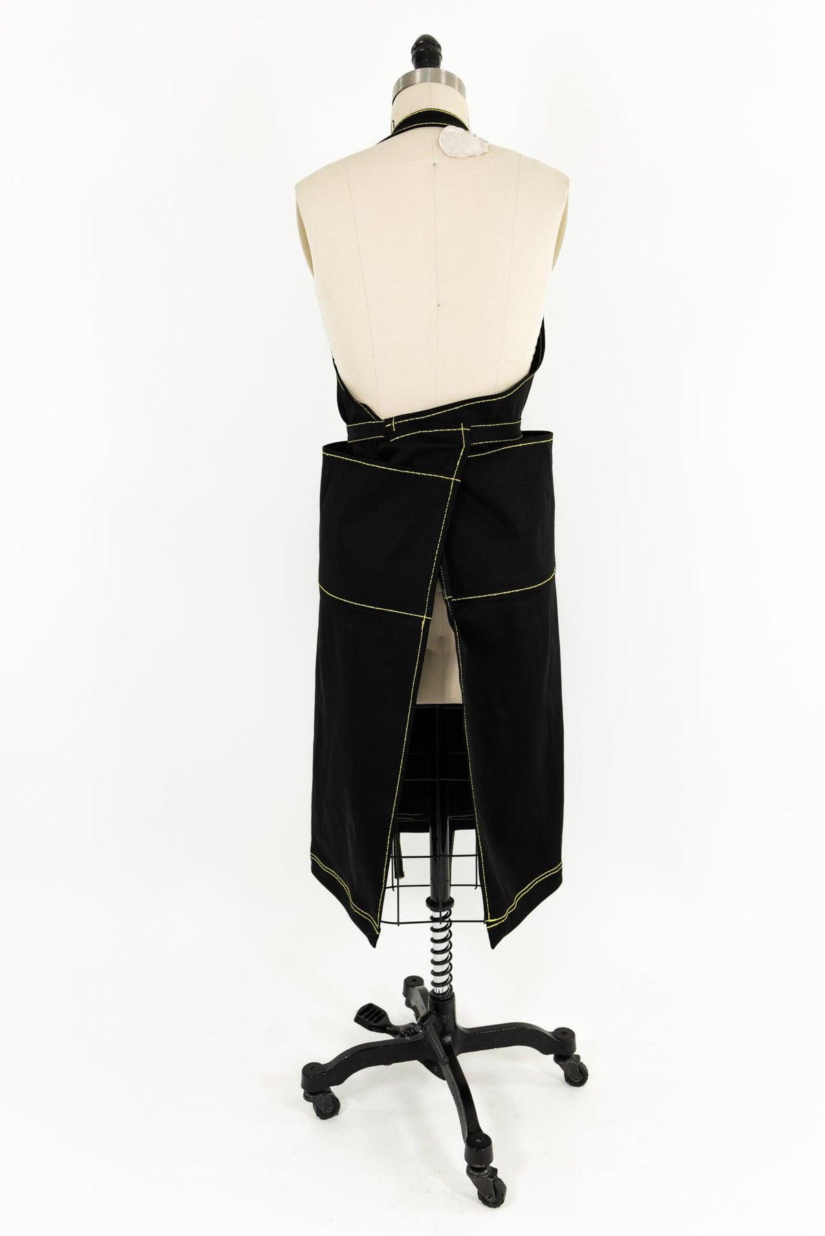 Black wrap skirt with yellow contrast stitching, displayed on dress form for sewing and fashion design