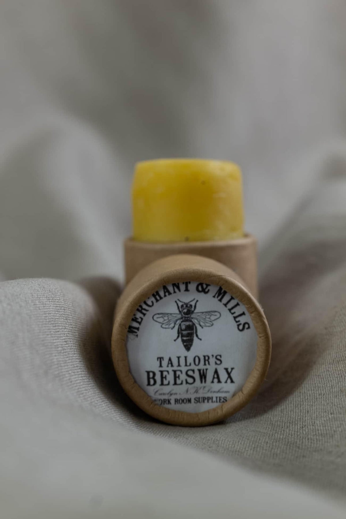 Tailor's beeswax in paper tube on fabric, sewing supply for quilting and apparel projects