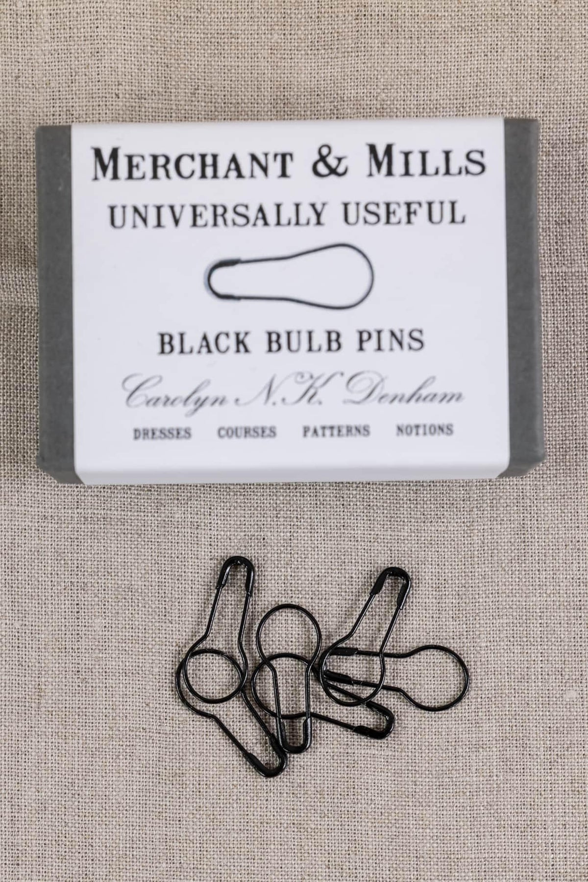 Black bulb pins by Merchant & Mills for sewing, dressmaking, and pattern work on textured fabric background