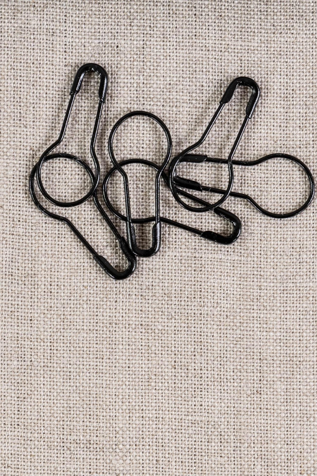 Black fabric clips on natural linen fabric for sewing and quilting projects