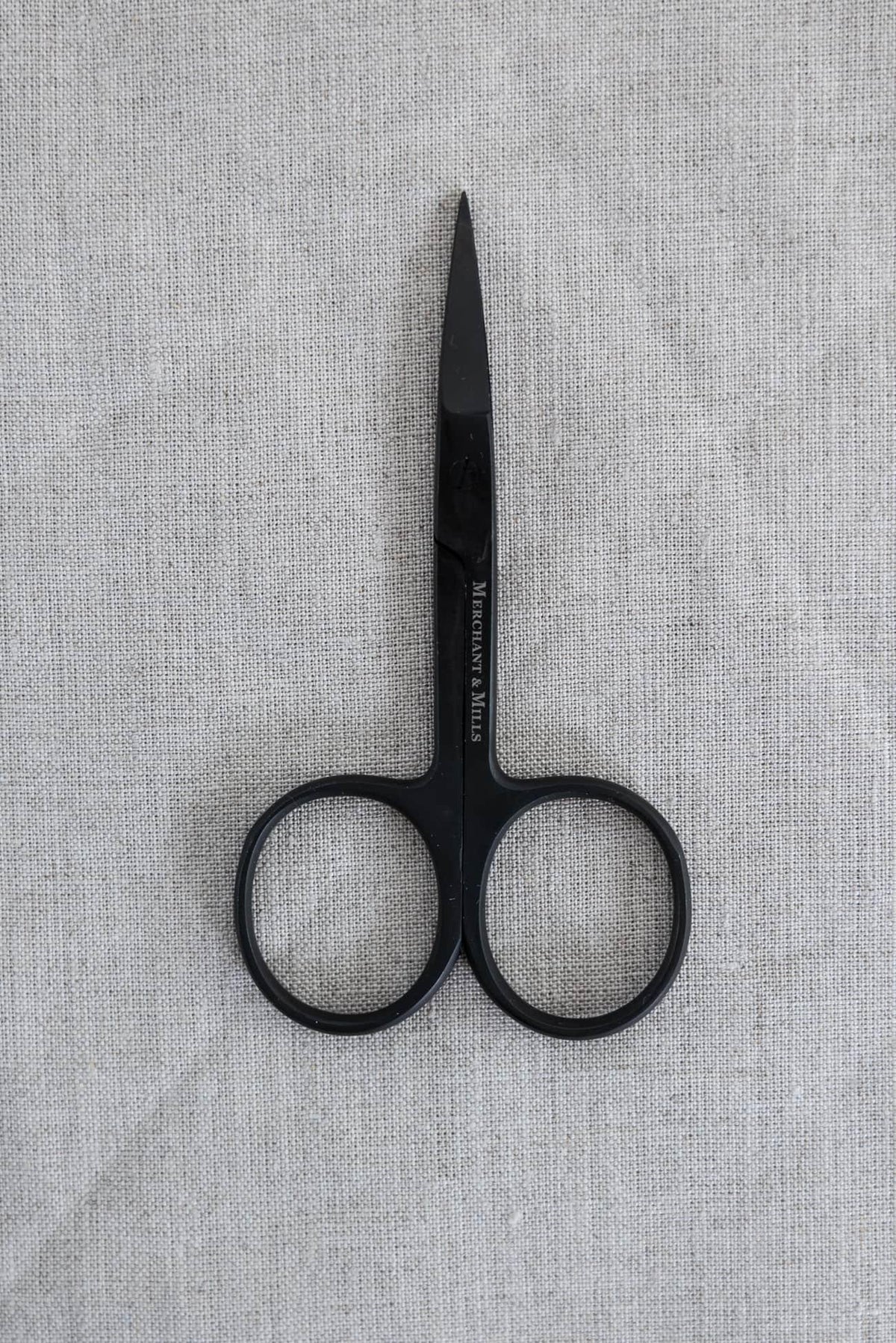 Black Merchant & Mills sewing scissors on textured linen fabric for apparel and quilting projects