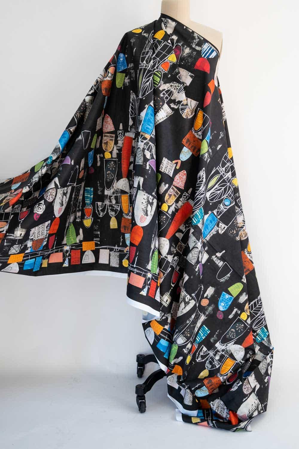 Black fabric with colorful abstract geometric print, draped on mannequin for sewing and apparel projects