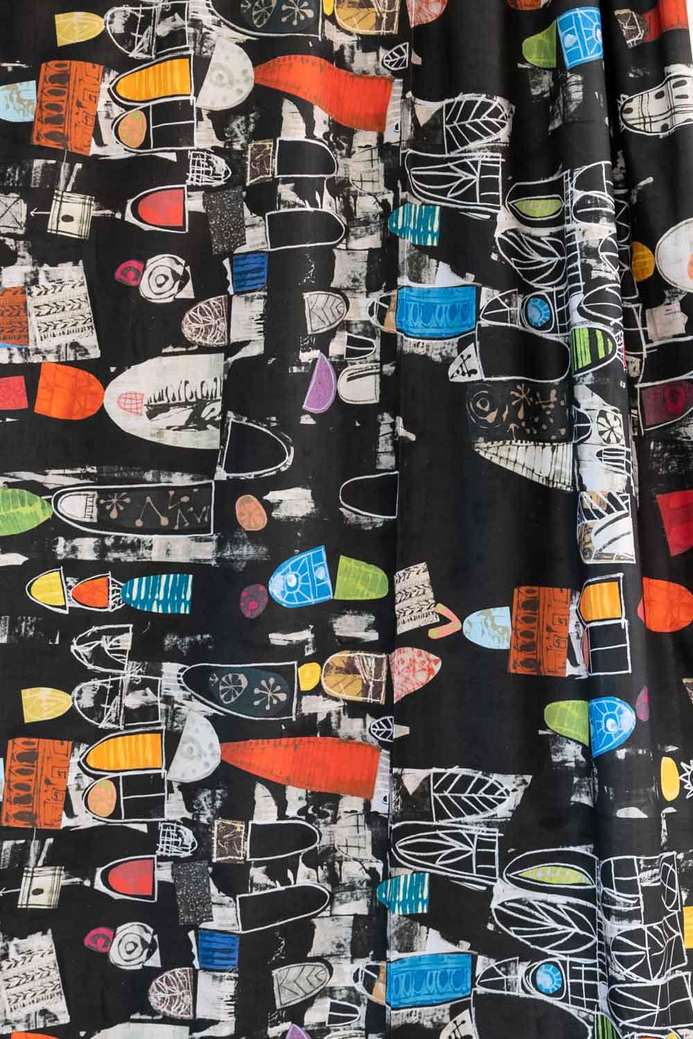 Bold abstract print fabric with colorful geometric shapes on black background, ideal for fashion sewing projects