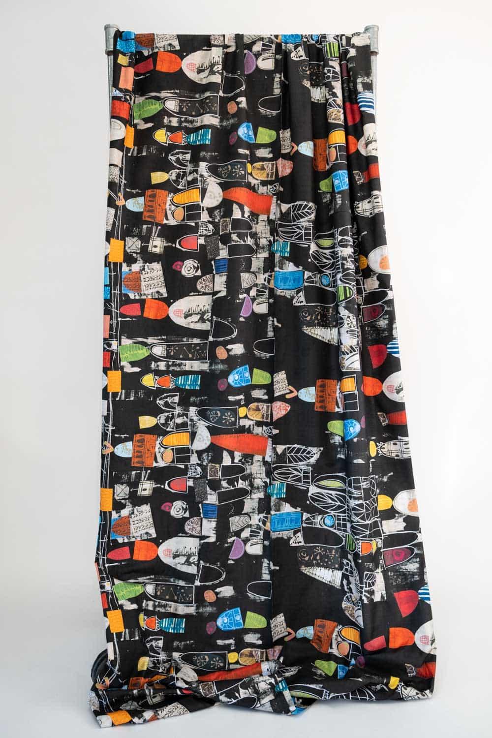 Black abstract print fabric with colorful geometric shapes, ideal for apparel and creative sewing projects.