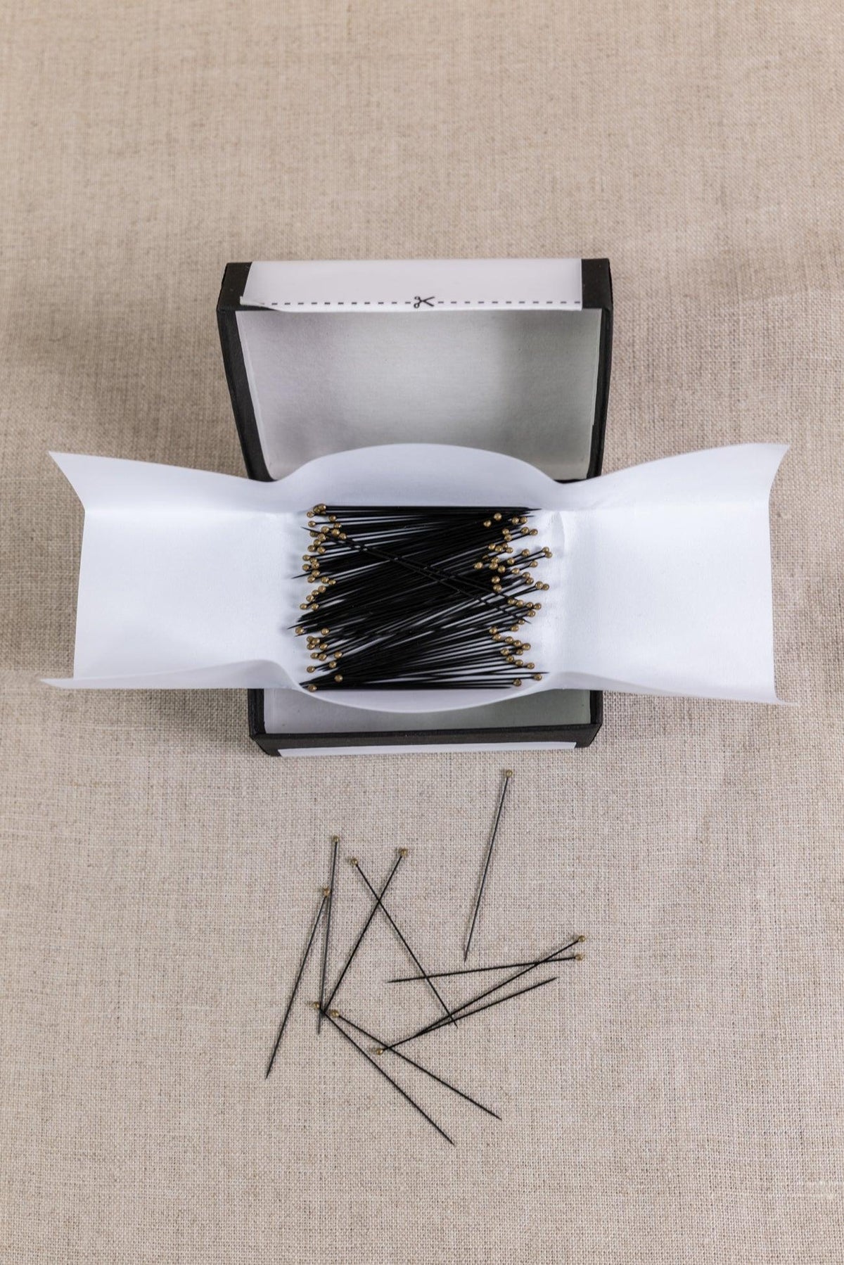 Black sewing pins with gold heads in a box, ideal for fabric crafts and apparel sewing projects
