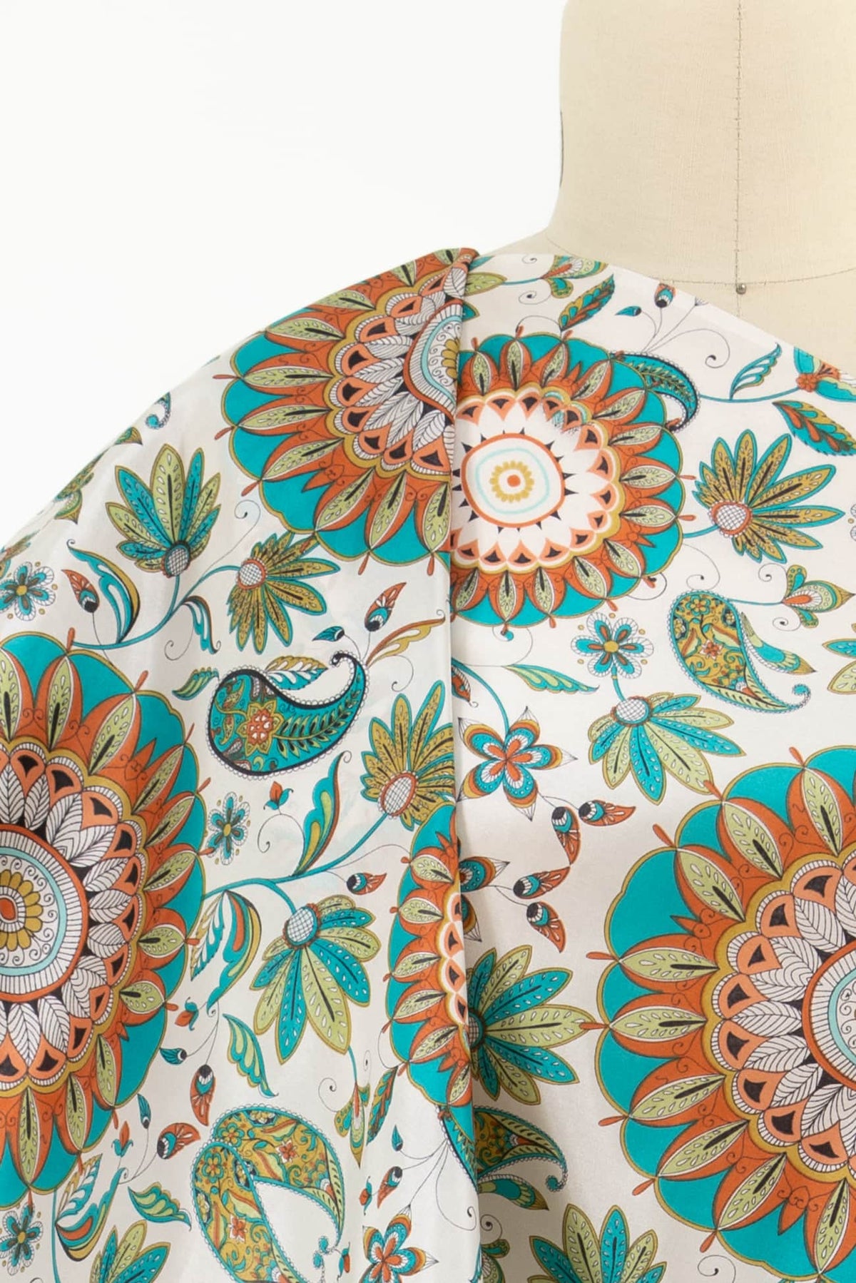 Vibrant floral and paisley print fabric in teal, orange, and green on white background, ideal for apparel and quilting.