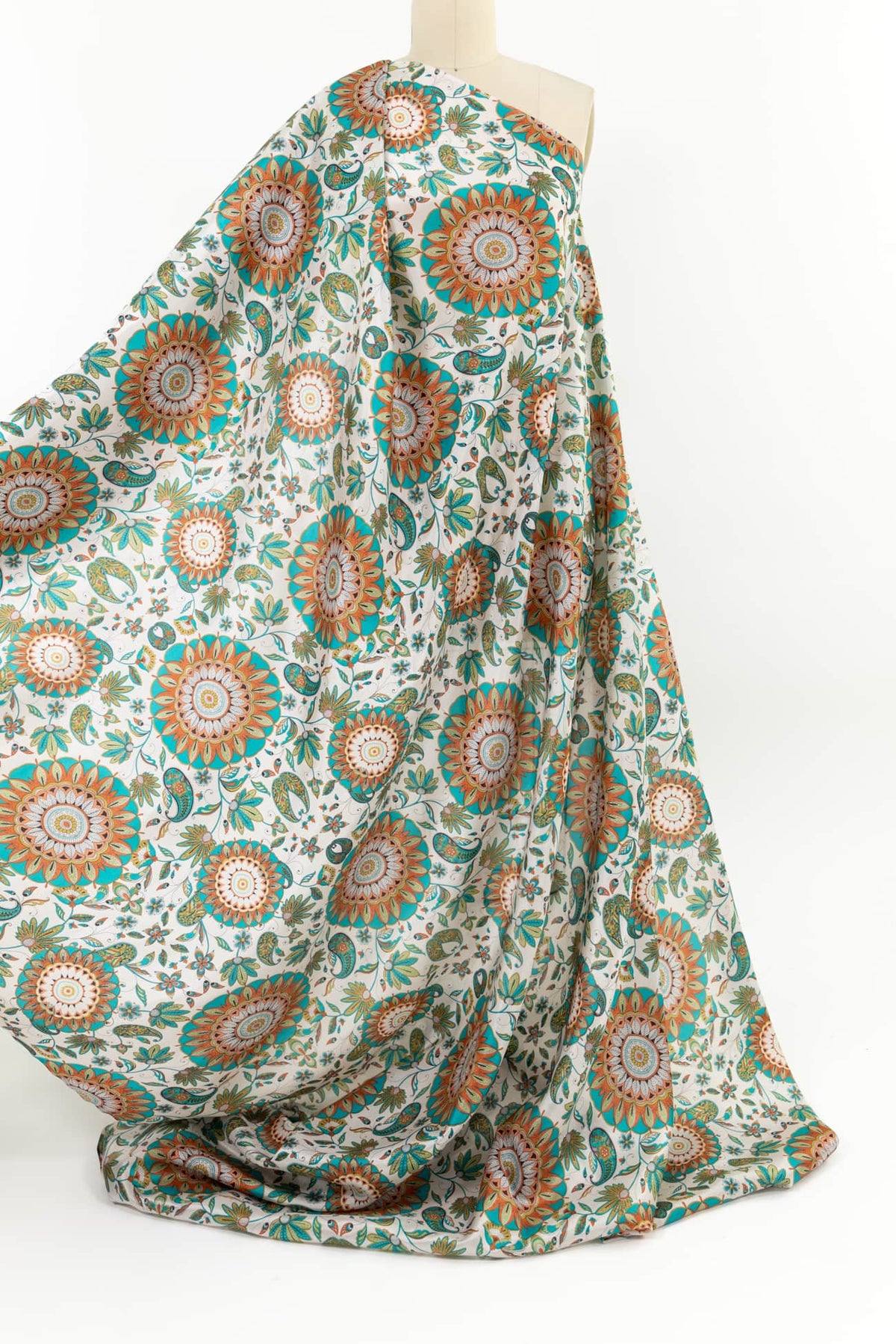 Floral and paisley print fabric in teal, orange, and green on white, ideal for apparel and quilting projects.