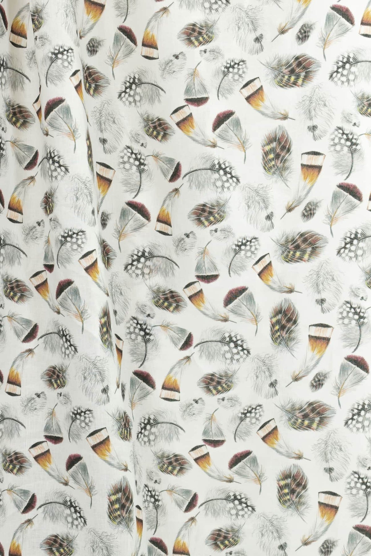 White fabric with colorful feather print, ideal for apparel and quilting projects