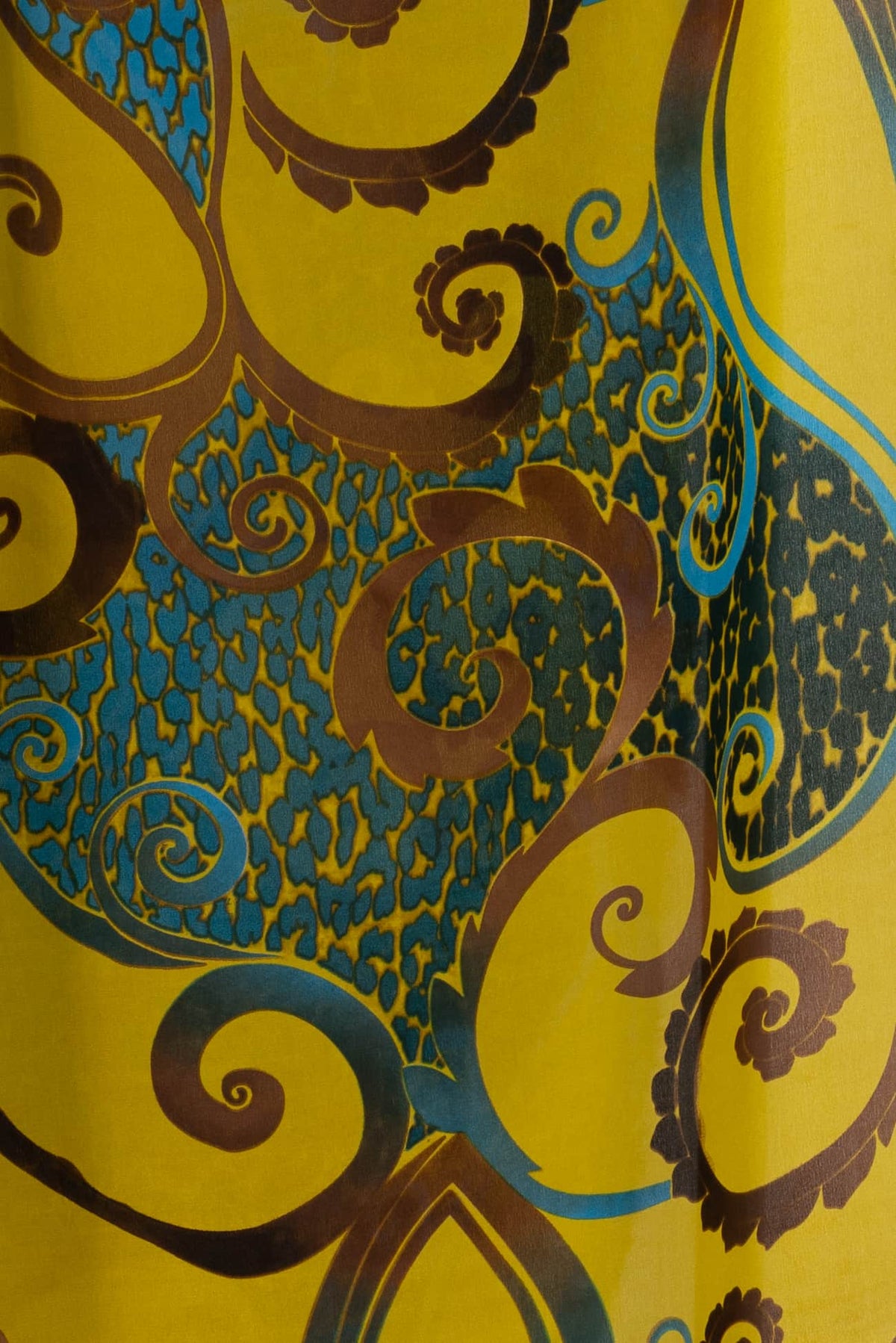 Vibrant yellow fabric with bold blue and brown swirls and abstract floral patterns, ideal for apparel and quilting.
