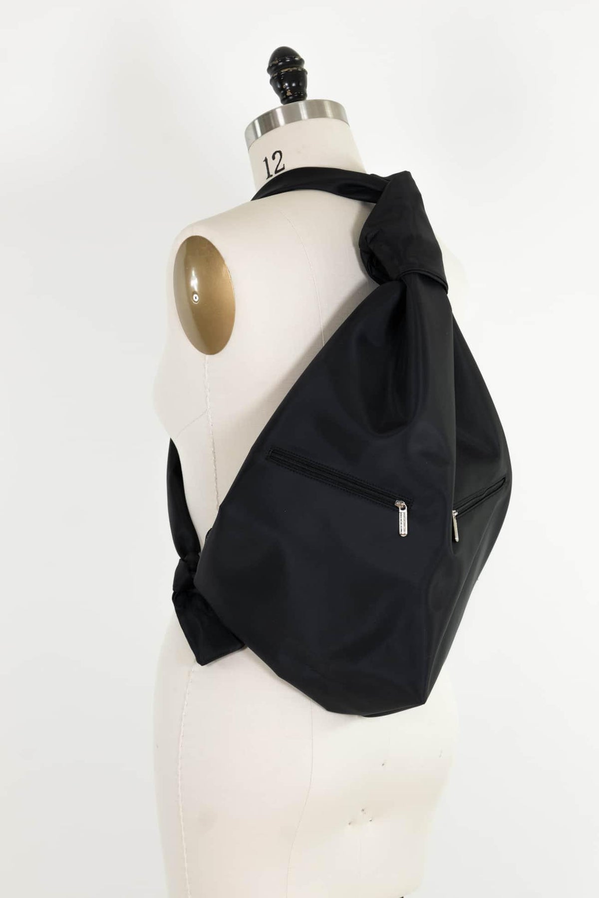 Black nylon crossbody bag with zipper pockets, styled on dress form for sewing and fashion projects