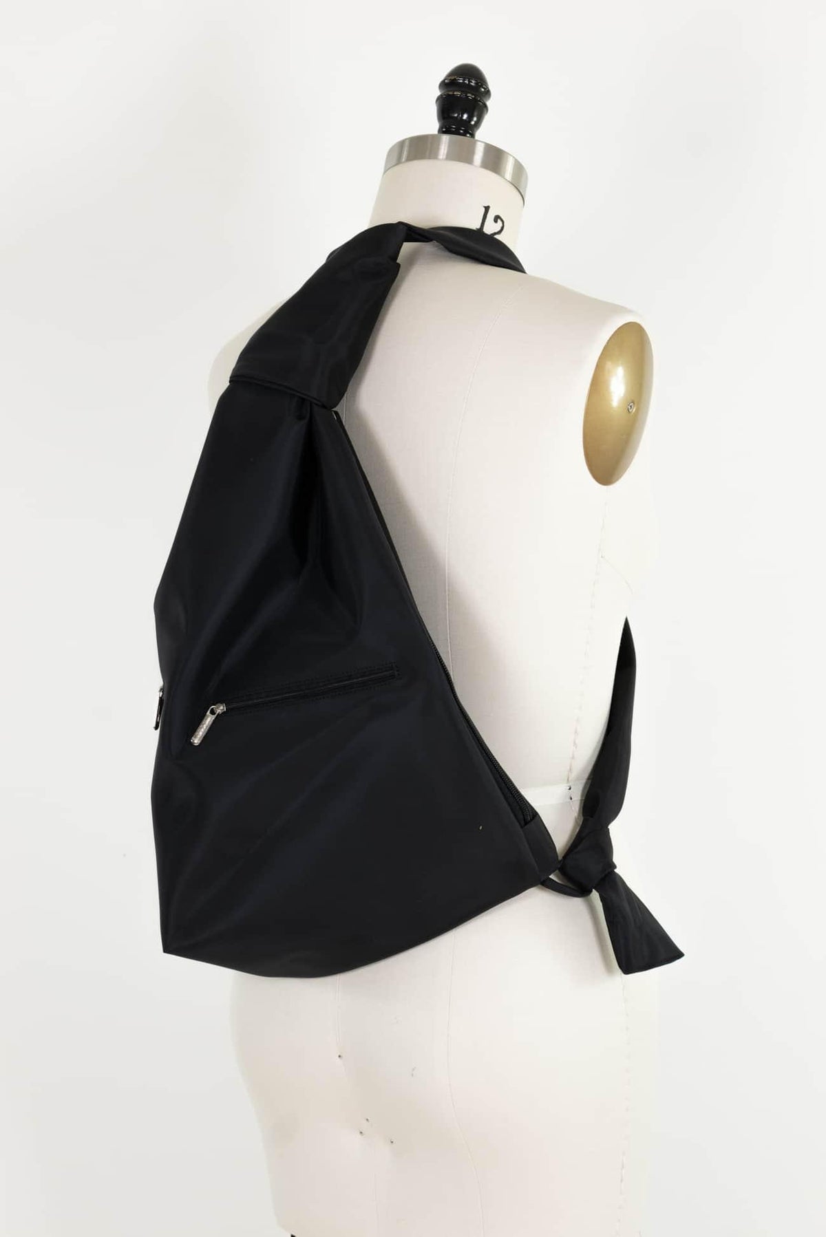 Black fabric sling bag with zipper pocket, displayed on mannequin for sewing and fashion projects