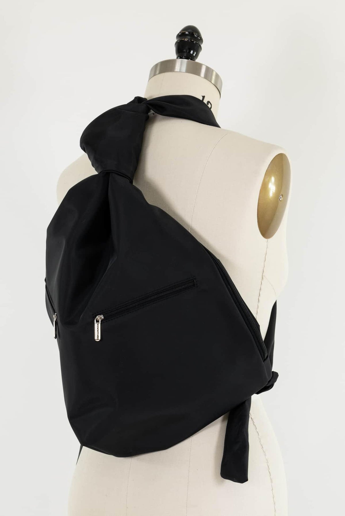 Black fabric crossbody bag with zipper pockets, styled on mannequin for sewing projects