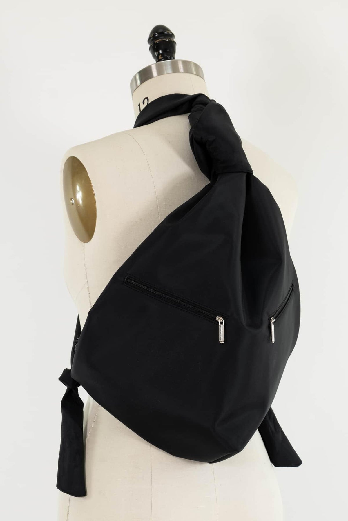 Black fabric crossbody bag with zipper pockets, styled on mannequin for sewing and fashion projects
