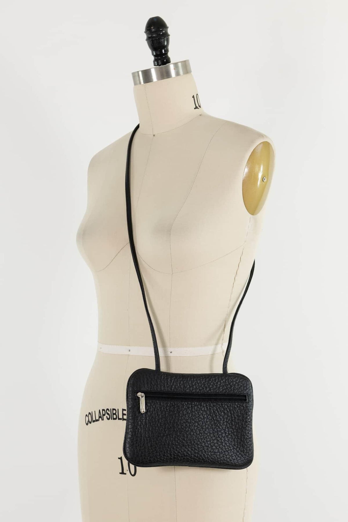 Black pebbled crossbody bag with zipper, displayed on dress form for sewing and fashion projects
