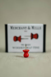 Red sewing pin with wooden head on fabric, ideal for quilting and apparel projects