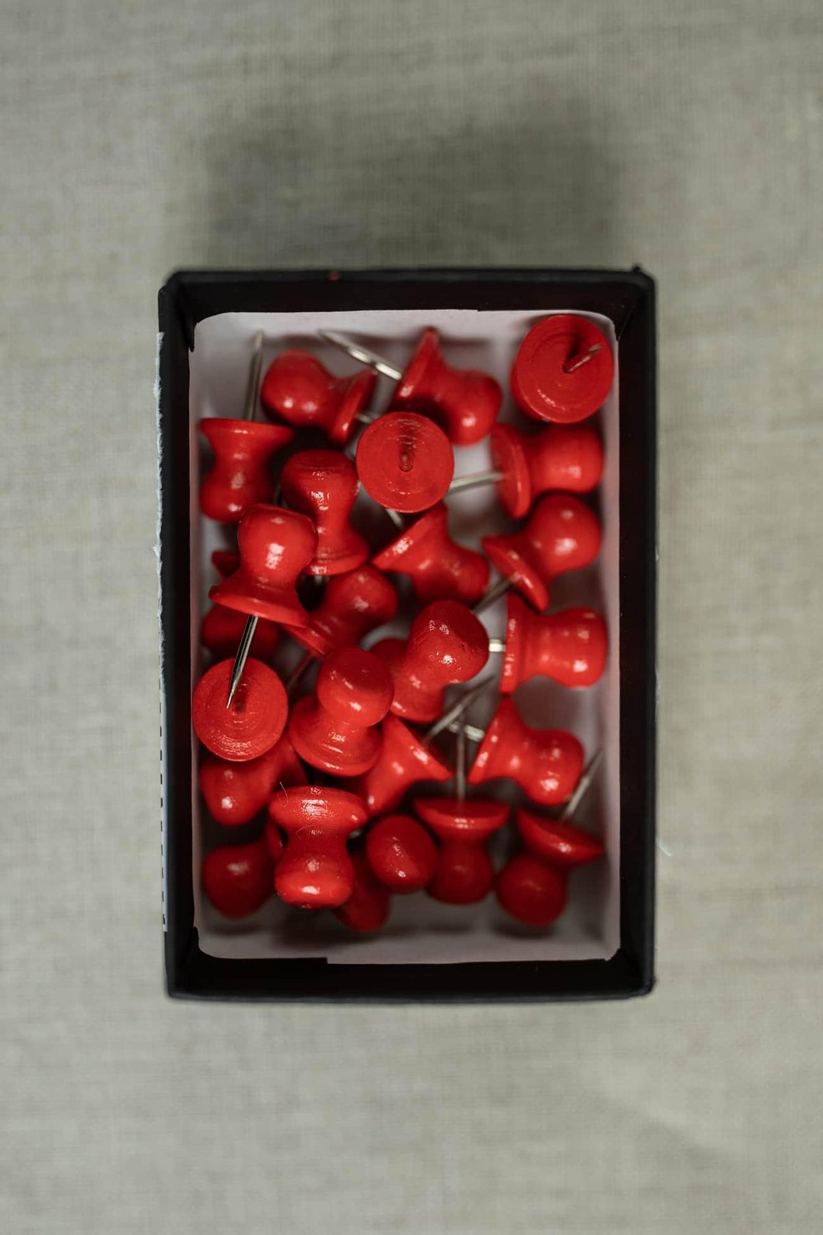 Red sewing pins in black box on fabric background for quilting and apparel projects