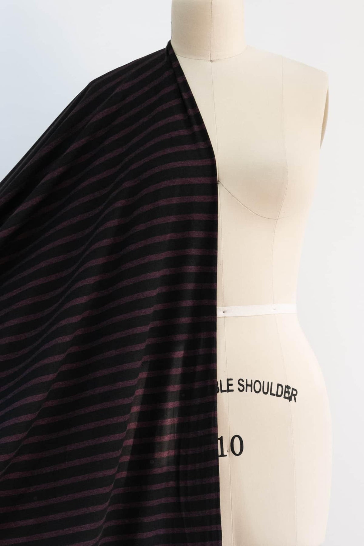 Black and burgundy striped knit fabric draped on dress form for sewing projects