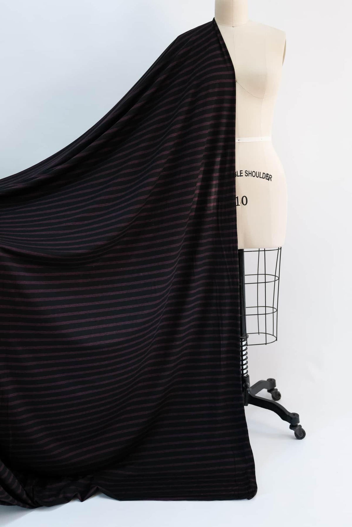 Black and burgundy striped knit fabric draped on dress form for sewing projects
