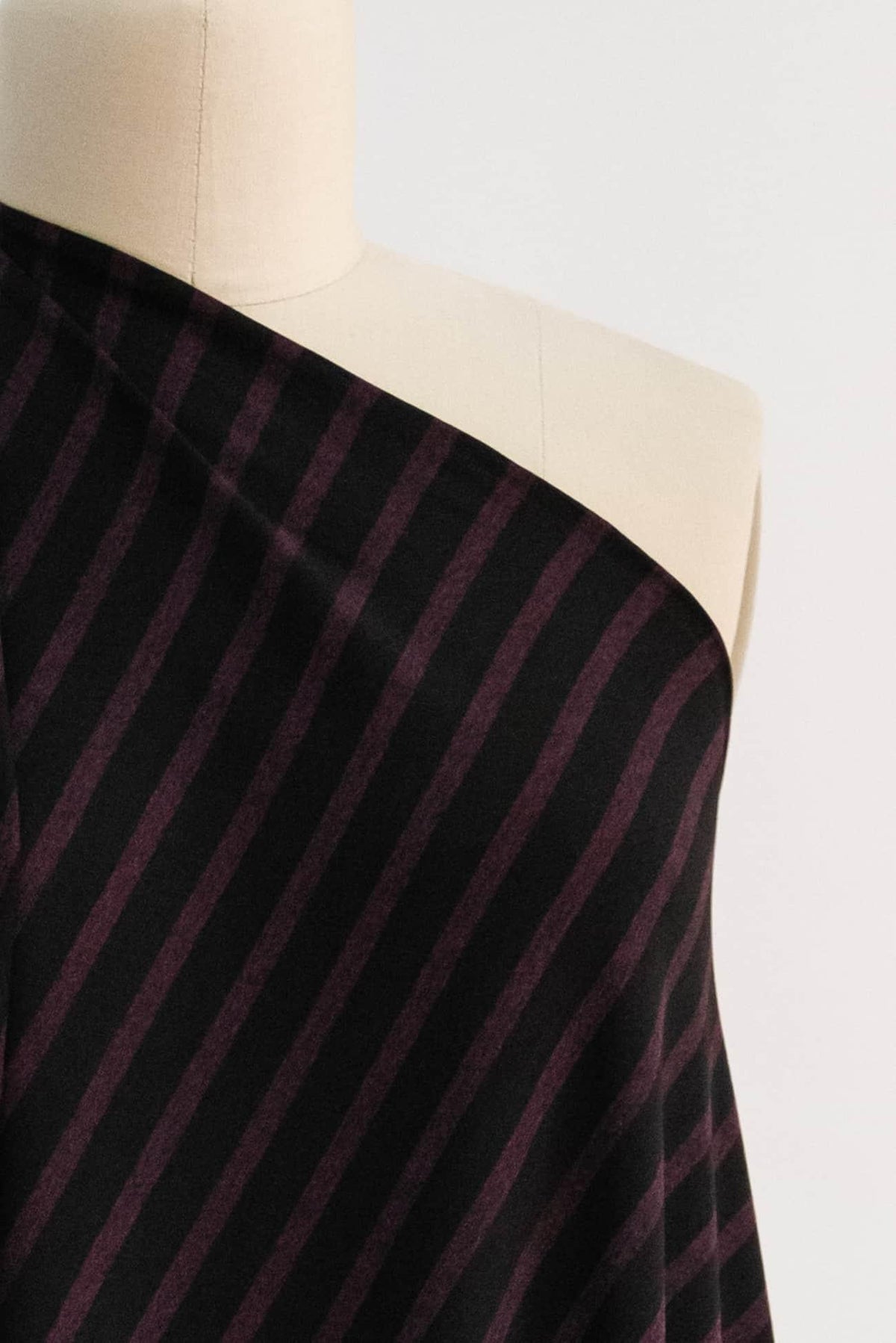 Black and burgundy striped fabric draped on mannequin, ideal for apparel sewing projects