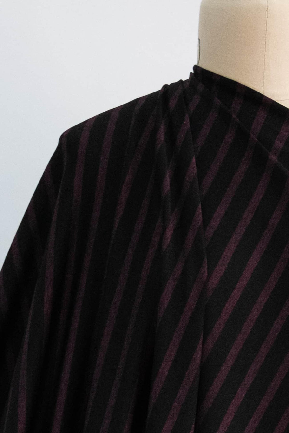 Black and burgundy striped fabric draped on mannequin, ideal for apparel sewing projects