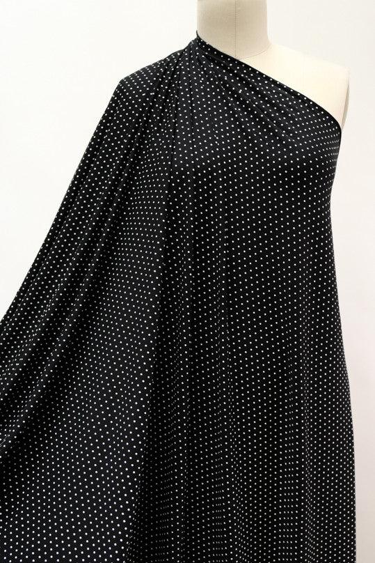 Black fabric with white polka dots, draped on mannequin for sewing projects