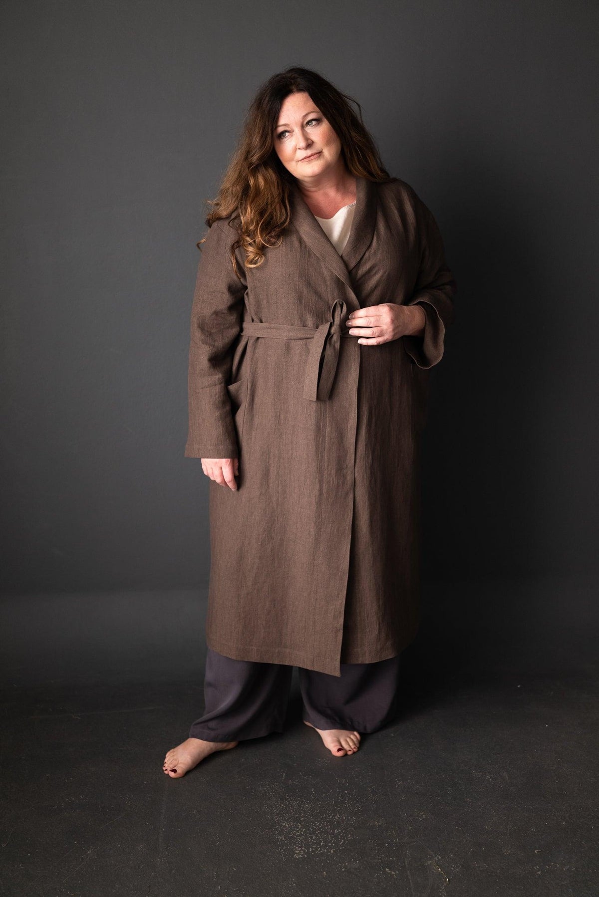 Woman in long brown linen wrap coat with belt, styled for sewing projects