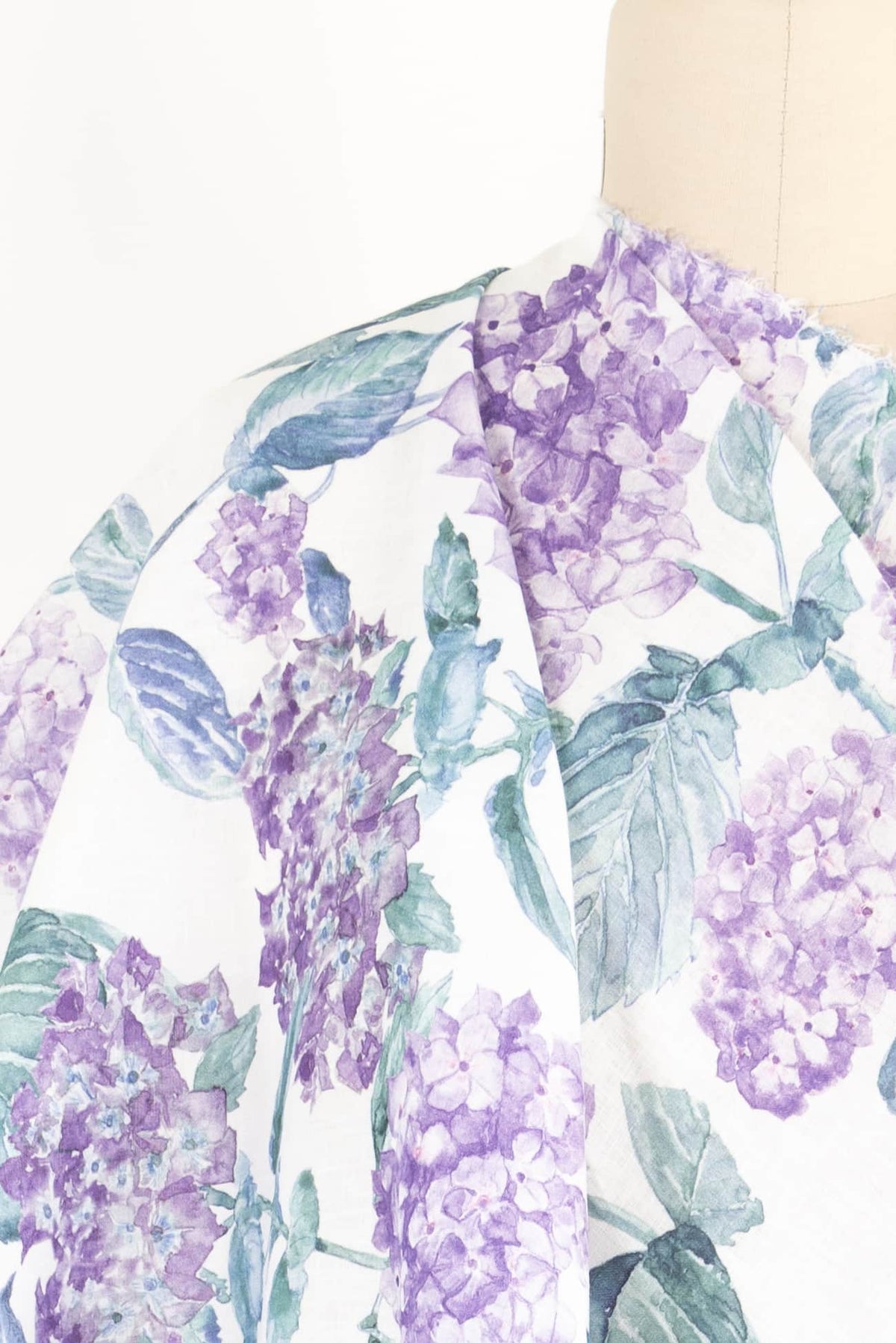 Purple hydrangea floral fabric with green leaves on white background, ideal for apparel sewing