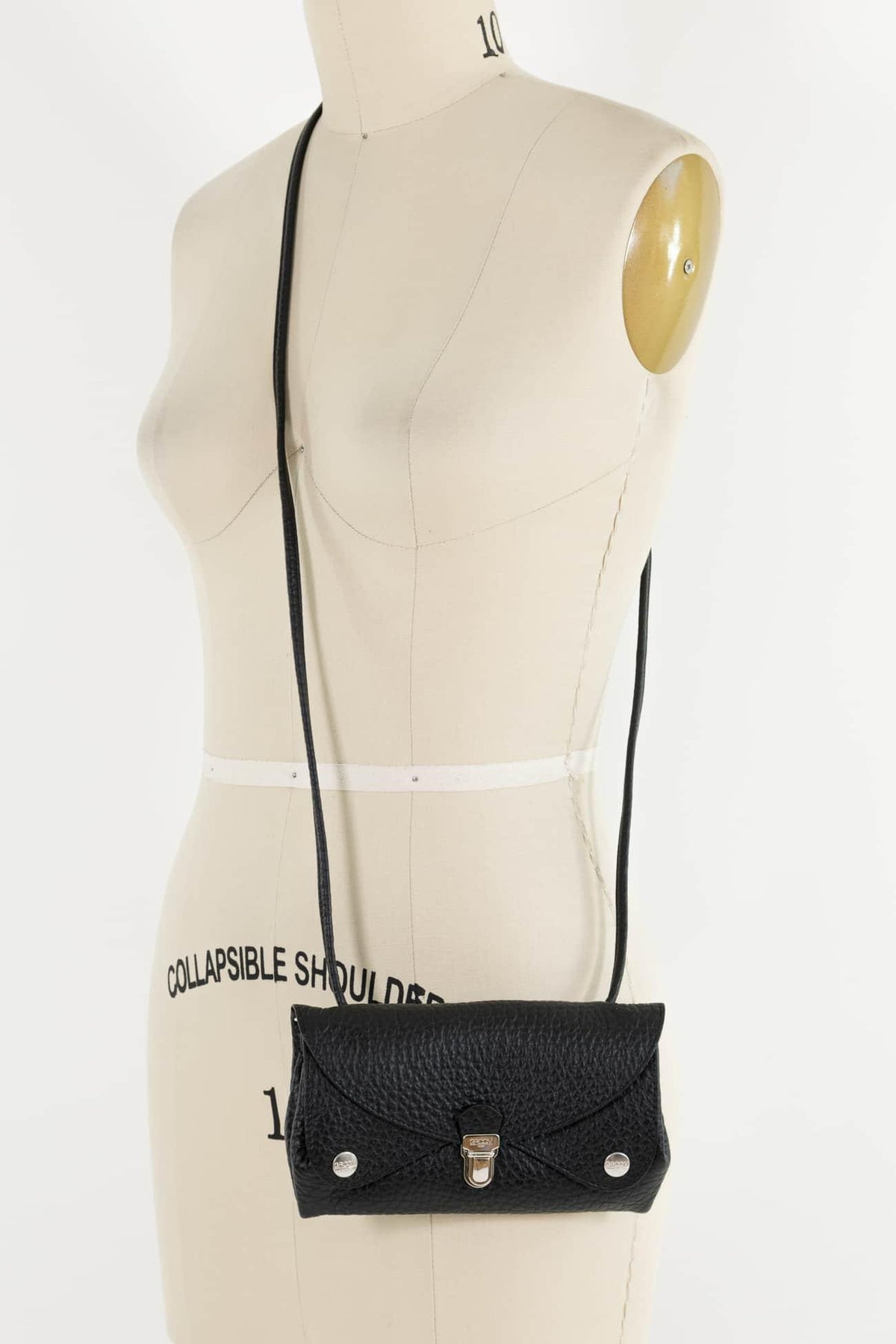 Black textured crossbody bag with gold clasp on dress form, ideal for fashion sewing projects
