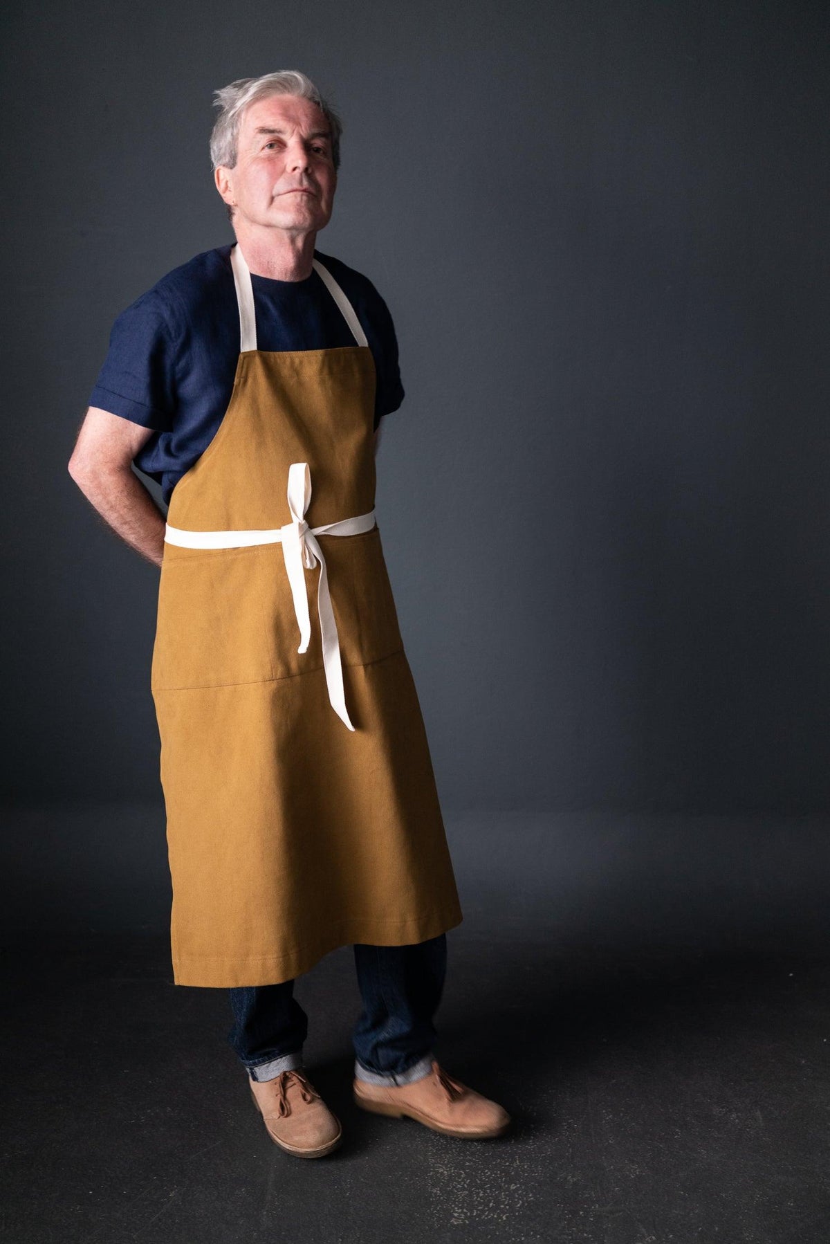 Man wearing mustard linen apron with white ties, ideal for sewing, crafting, or kitchen use