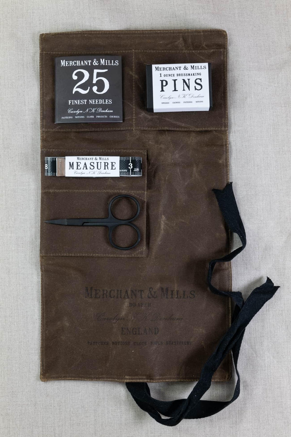 Merchant & Mills sewing kit with needles, pins, tape measure, and scissors in a brown fabric roll
