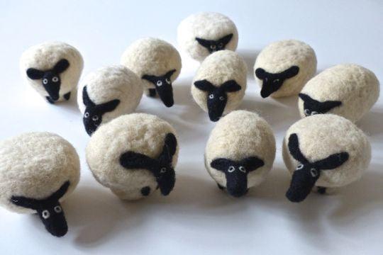 Felted wool sheep ornaments, handmade with black faces and white wool bodies, perfect for crafting or decor