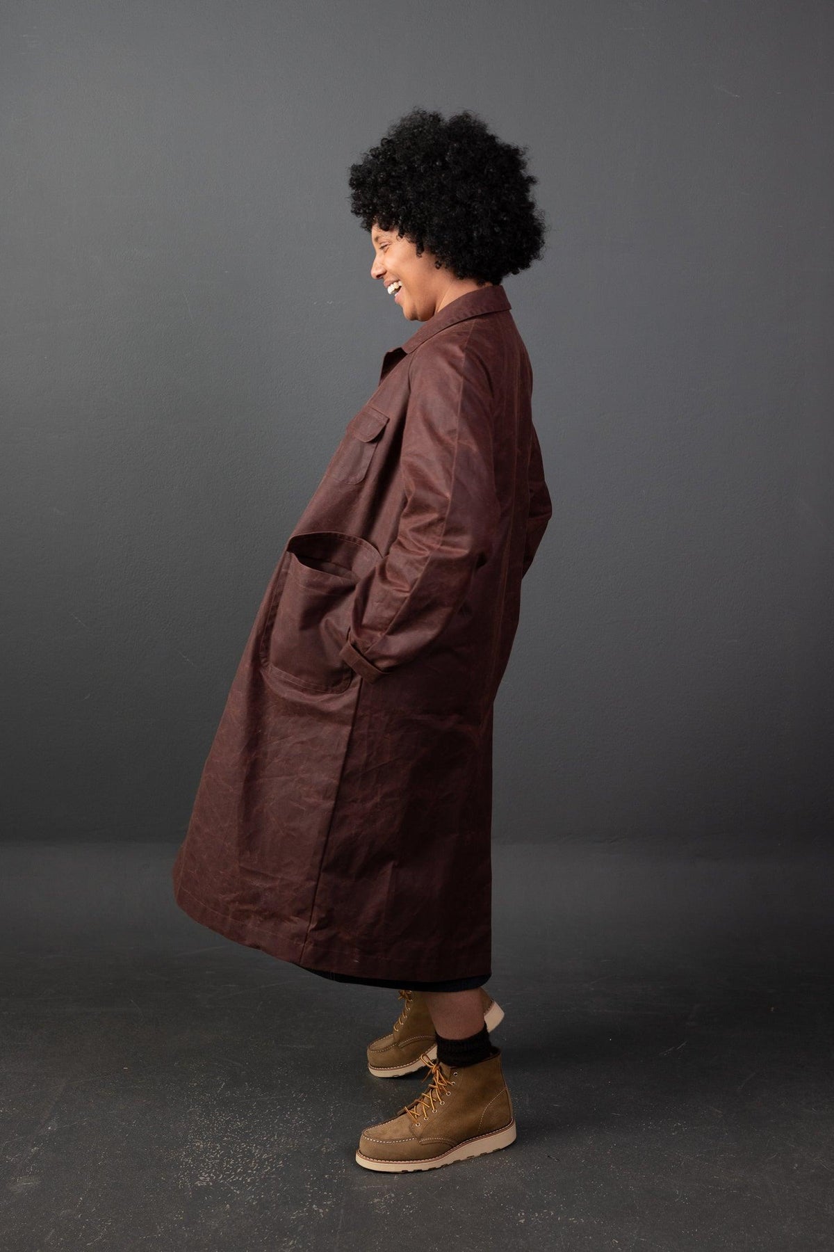 Woman in rich burgundy waxed cotton coat with large pockets, styled for fall sewing projects