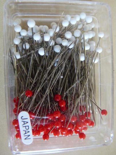 Clear box of white and red ball-head sewing pins, labeled Japan, for fabric crafting and garment construction