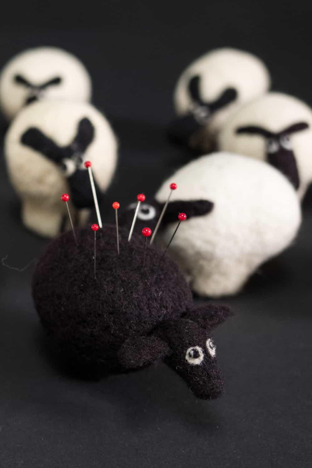 Felt sheep pin cushion with red-headed pins, perfect for sewing and quilting projects